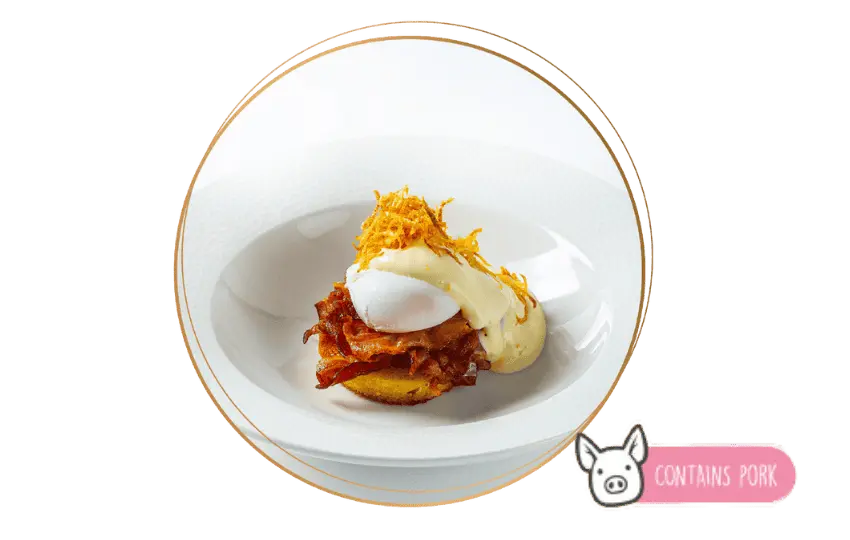 Mélytányérban tálalt New York egg Benedict. Angol muffin, bacon, bevert tojás, hollandi mártás, szalmaburgonya